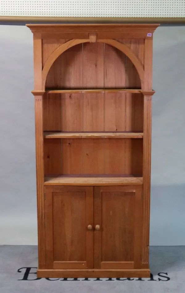 A modern pine floor standing open bookcase with three shelves over a pair of cupboards