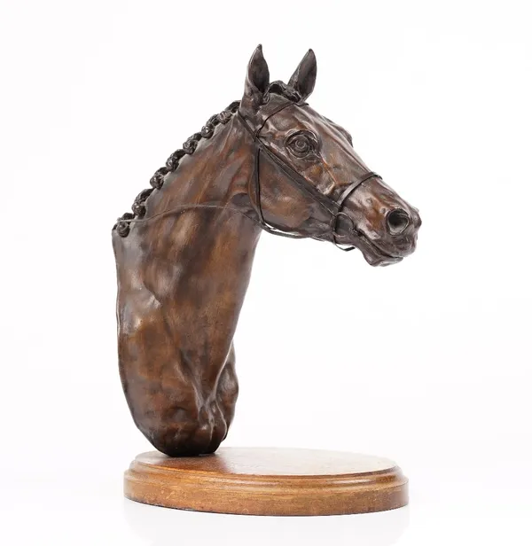 A bronzed model of a horse head mounted on an oval wooden plinth