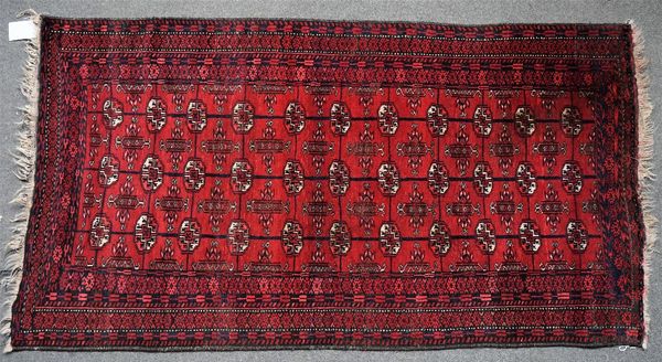 An Afghan Turkman rug, the madder field with three columns of eleven guls with various borders, 183cm x 100cm, and a Caucasian rug with five...