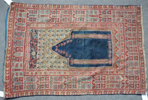 An antique Ghiordes prayer rug, Turkish, the plain indigo mehrab with two columns, a flower filled arch above and an ivory flower filled border,...