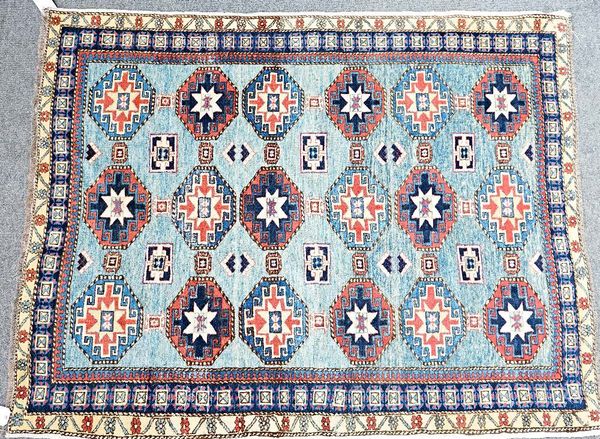 A Caucasian rug, the pale indigo field with three columns of six guls, supporting motifs; an indigo sunburst border, 200cm x 162cm.