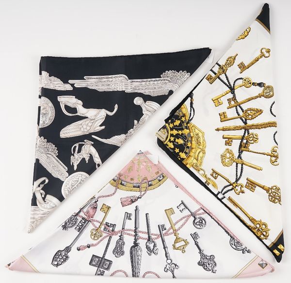 A collection of three Hermes print silk scarves, comprising: a 'Les Parure du Vent' designed by Joachim Metz in pinks and greys to a black ground,...