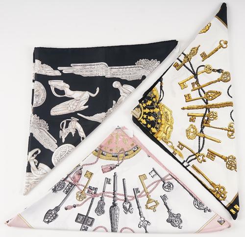 A collection of three Hermes print silk scarves, comprising: a 'Les Parure du Vent' designed by Joachim Metz in pinks and greys to a black ground,...