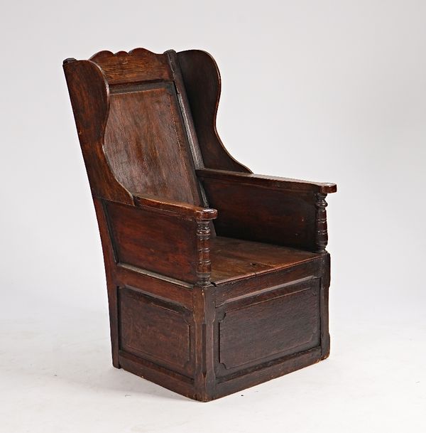 An 18th century oak lambing chair with lift box seat, 67cm wide x 112cm high.