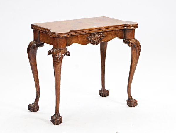 A mid-18th century style walnut consertina action card table, with dished gaming wells, on claw and ball supports, 86cm wide x 73cm high.