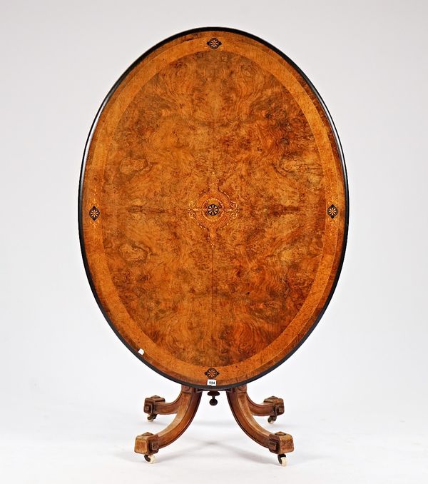 A Victorian marquetry inlaid figured walnut snap top oval centre table, on four downswept supports, 130c,m wide x 74cm high.