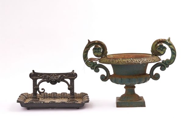 A BLACK PAINTED CAST IRON BOOT SCRAPER AND A GREEN PAINTED GARDEN URN