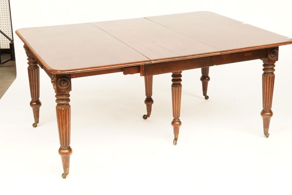 A REGENCY MAHOGANY EXTENDING DINING TABLE ON REEDED SUPPORTS