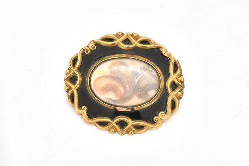 A GEORGE III SHAPED OVAL BLACK ENAMELLED MOURNING BROOCH
