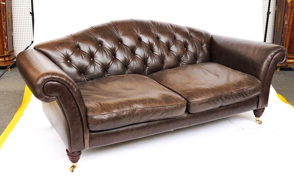 A BROWN LEATHER UPHOLSTERED HUMP BACK SOFA ON TURNED SUPPORTS