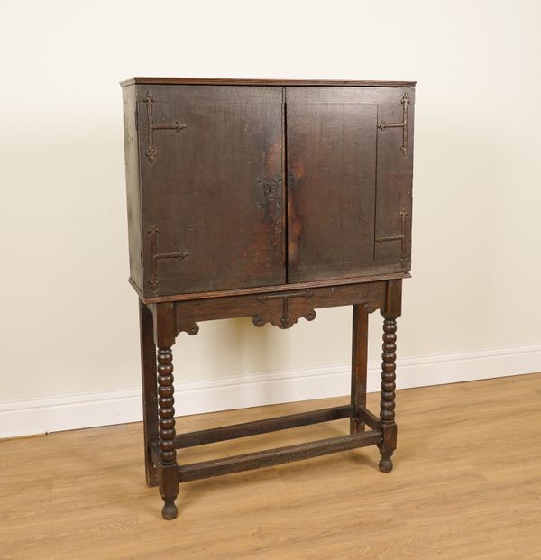 A 17TH CENTURY AND LATER OAK TWO DOOR CUPBOARD ON BOBBIN TURNED BASE