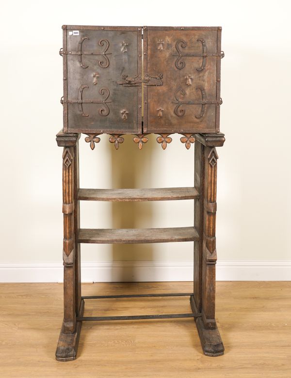 A SHEET IRON TWO DOOR CUPBOARD ON A FRENCH GOTHIC REVIVAL CARVED OAK STAND