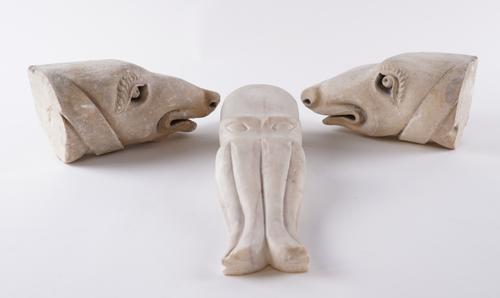 A PAIR OF CARVED STONE MEDIEVAL STYLE DOG HEAD FINIALS OR BOOKENDS AND A CARVED MARBLE OCTOPUS (3)