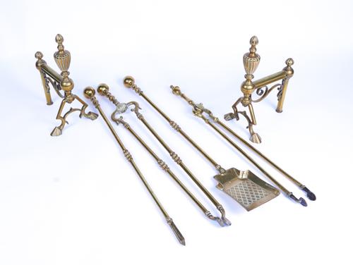 AN EDWARDIAN PIERCED BRASS ROCOCO STYLE SERPENTINE FENDER TOGETHER WITH A GROUP OF FIRE TOOLS (7)