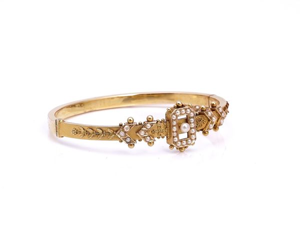 A VICTORIAN GOLD AND SEED PEARL SET HINGED BANGLE