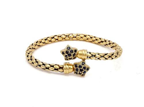 A GOLD AND SAPPHIRE SPRUNG BANGLE