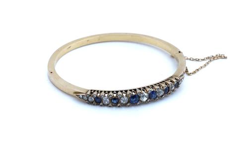 A GOLD, SAPPHIRE AND DIAMOND OVAL HINGED BANGLE