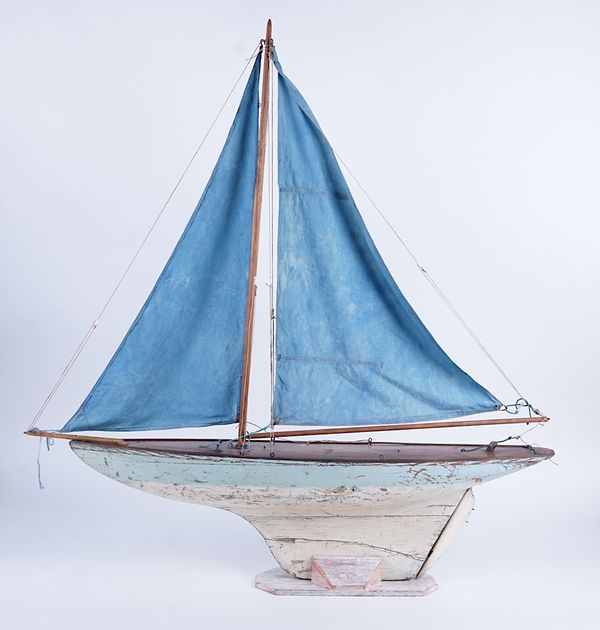 A WOODEN POND YACHT WITH BLUE SAILS AND A POND YACHT HULL