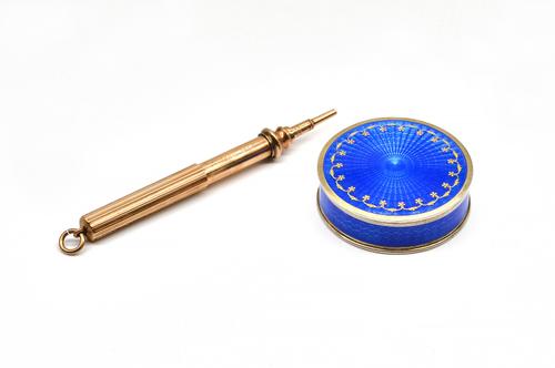 A SILVER GILT AND BLUE ENAMELLED CIRCULAR HINGE LIDDED BOX AND A GOLD CASED PROPELLING PENCIL (2)