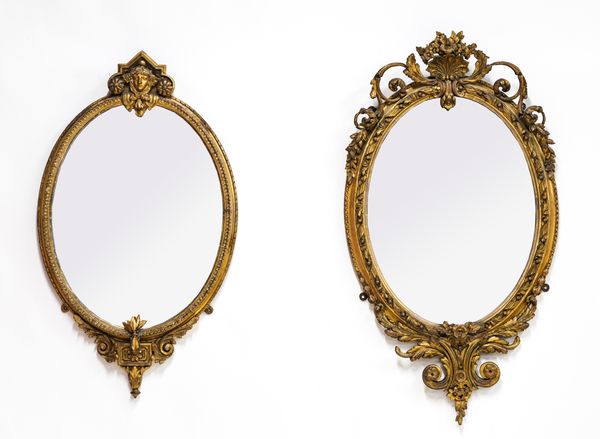 A LATE 19TH CENTURY OVAL GILT FRAMED MIRROR WITH MASK DECORATION (2)