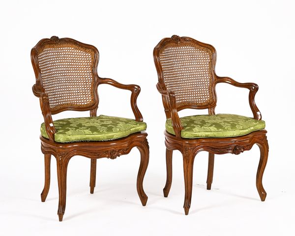 A PAIR OF LOUIS XV CARVED WALNUT FRAMED OPEN ARMCHAIRS