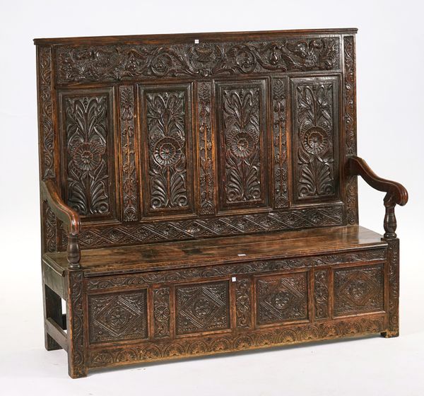 A VICTORIAN CARVED OAK FOUR PANEL BACK SETTLE