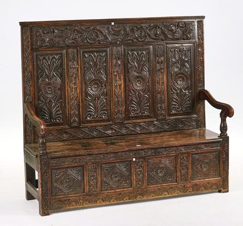 A VICTORIAN CARVED OAK FOUR PANEL BACK SETTLE