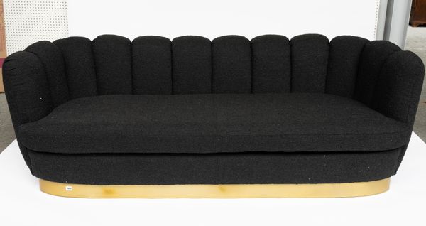 A BLACK UPHOLSTERED SHELL BACK SOFA ON GOLD PLINTH BASE