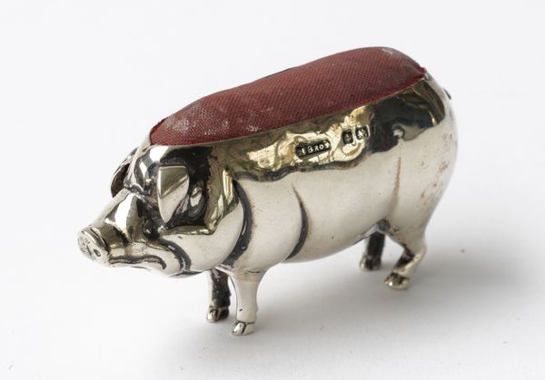 A SILVER PIN CUSHION MODELLED AS A STANDING PIG