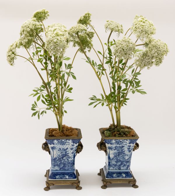 A PAIR OF GILT-METAL MOUNTED BLUE AND WHITE CHINOISERIE DECORATED CERAMIC JARDINIERES (2)