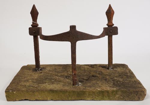 A WROUGHT IRON BOOT SCRAPER ON STONE BASE