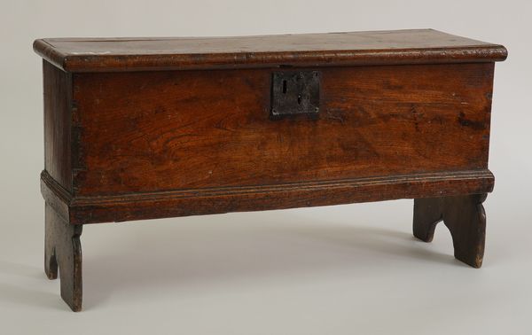 A MINIATURE 18TH CENTURY ELM COFFER ON SILHOUETTE SLAB ENDS