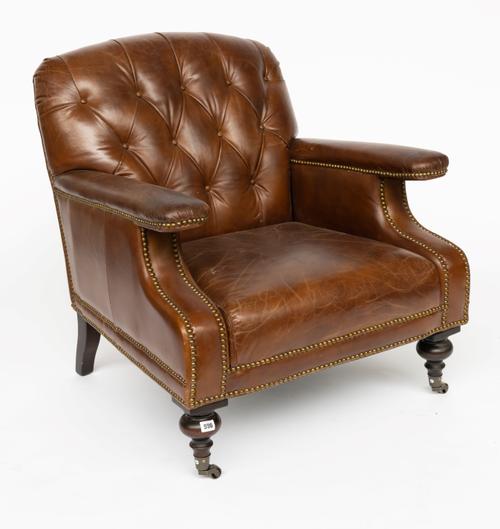 A STUDDED TAN LEATHER UPHOLSTERED EASY ARMCHAIR ON TURNED SUPPORTS