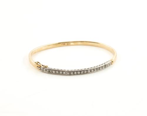 A GOLD AND DIAMOND SET OVAL HINGED BANGLE