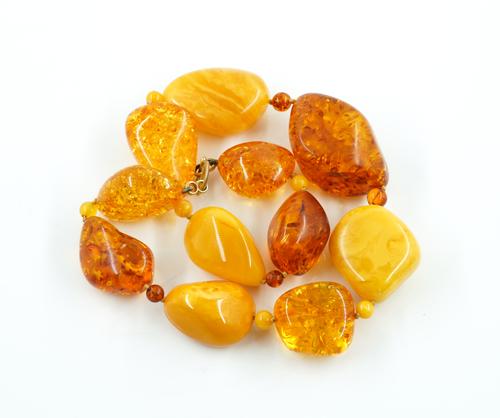 A SINGLE ROW NECKLACE OF VARICOLOURED LARGE AMBER BEADS