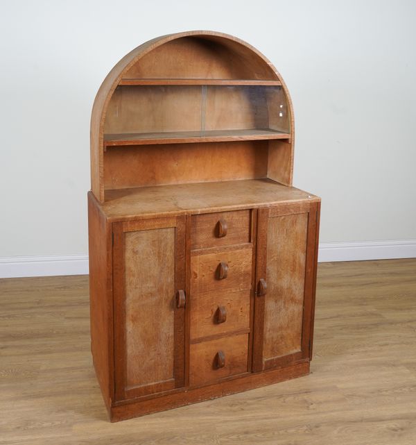 HEAL'S TOTTENHAM COURT ROAD, LONDON W1; A LIMED OAK DOME TOPPED SIDE CABINET WITH SLIDING GLAZED DOOR SHELF BACK OVER FOUR DRAWERS FLANKED BY CUPBOARDS