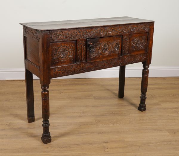 A 17TH CENTURY OAK HUTCH CUPBOARD WITH CARVED FRONT PANEL ON TURNED SUPPORTS