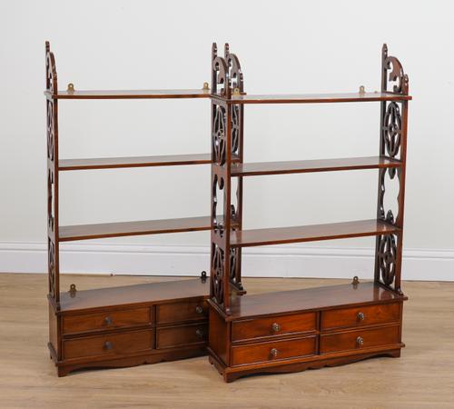 A PAIR OF GEORGE III STYLE MAHOGANY FOUR TIER SHELVES EACH WITH FOUR DRAWER BASE AND FRET CARVED SIDES (2)