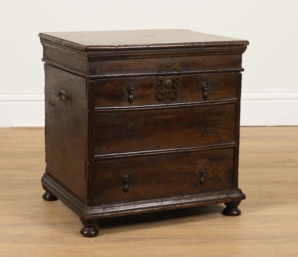 A 17TH CENTURY OAK LIFT TOP BOX STOOL MODELLED AS A DIMINUTIVE CHEST OF DRAWERS