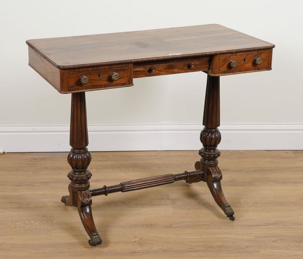 A REGENCY ROSEWOOD THREE DRAWER WRITING DESK ON TWIN REEDED SUPPORTS