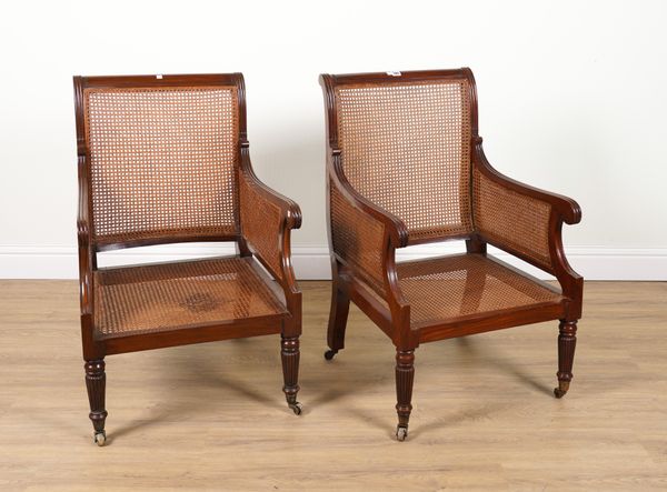 A PAIR OF REGENCY STYLE HARDWOOD FRAMED LIBRARY BERGERE ARMCHAIRS ON TAPERING REEDED SUPPORTS (2)