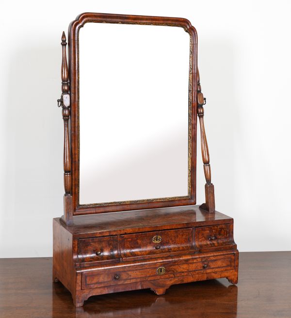 A GEORGE I PARCEL GILT WALNUT TOILET MIRROR WITH CUSHION FOUR DRAWER BASE