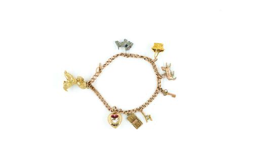 A 9CT GOLD CURB LINK BRACELET FITTED WITH EIGHT PENDANTS AND CHARMS