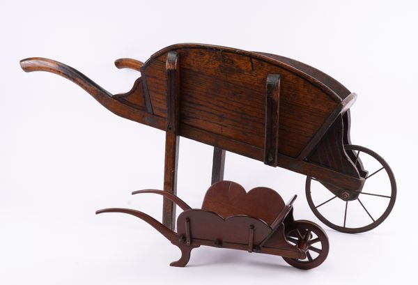 A LATE VICTORIAN MAHOGANY AND BRASS MOUNTED TABLE WHEEL BARROW AND AN ELM CHILD’S WHEEL BARROW OR A LIBRARY BOOK BARROW (2)