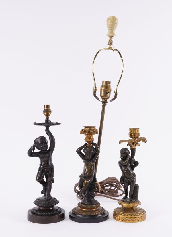 TWO FRENCH GILT AND PATINATED BRONZE FIGURAL CHERUB CANDLESTICKS AND A VICTORIAN BRONZE CHERUB TABLE LAMP (3)