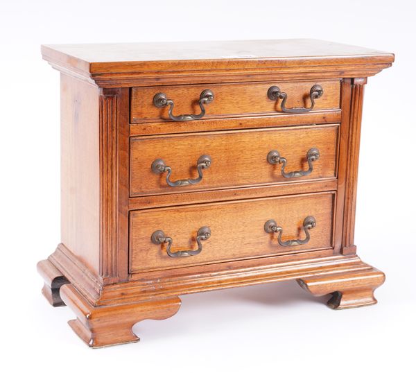 A MINIATURE WALNUT THREE DRAWER CHEST OF DRAWERS ON OGEE BRACKET FEET