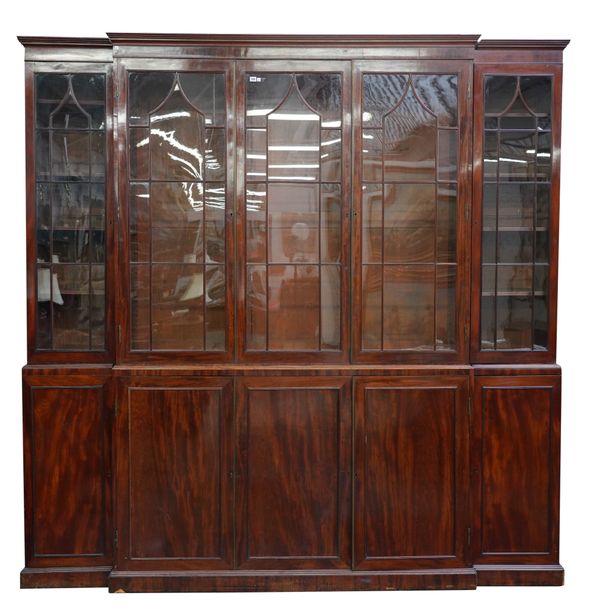 A GEORGE III MAHOGANY BREAKFRONT BOOKCASE CABINET WITH FIVE ASTRAGAL GLAZED DOORS OVER PANELLED CUPBOARDS ON PLINTH BASE