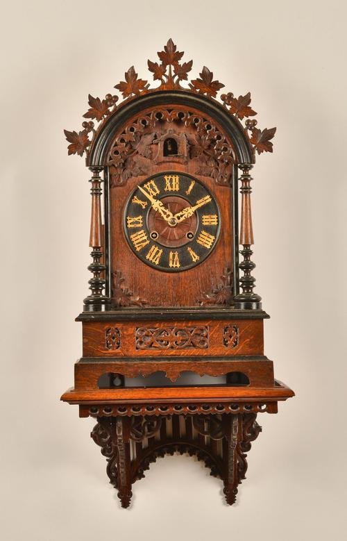 A GERMAN OAK CASED CUCKOO CLOCK AND BRACKET