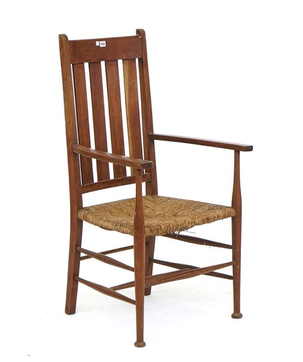 An Arts & Crafts teak framed rush seat open armchair