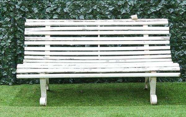 A white painted wrought iron and slatted wood garden bench